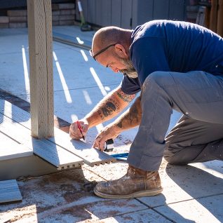 A man is laying laminate flooring.